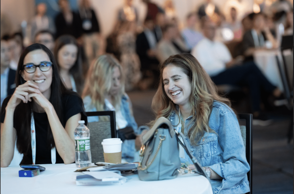 Two attendees at CommerceNext sit and chat with each other.
